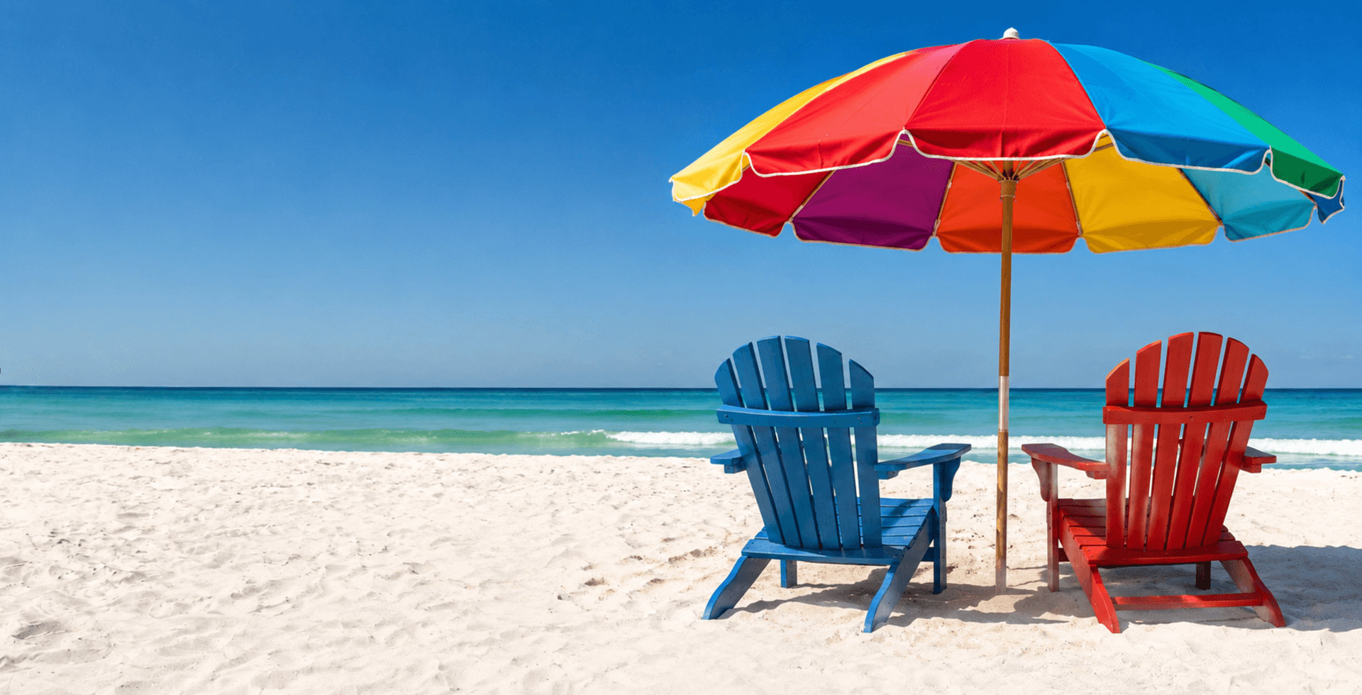 Beach scene with two colorful chairs and an umbrella